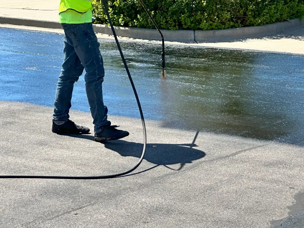 Crew member spraying sealcoat on an asphalt lot